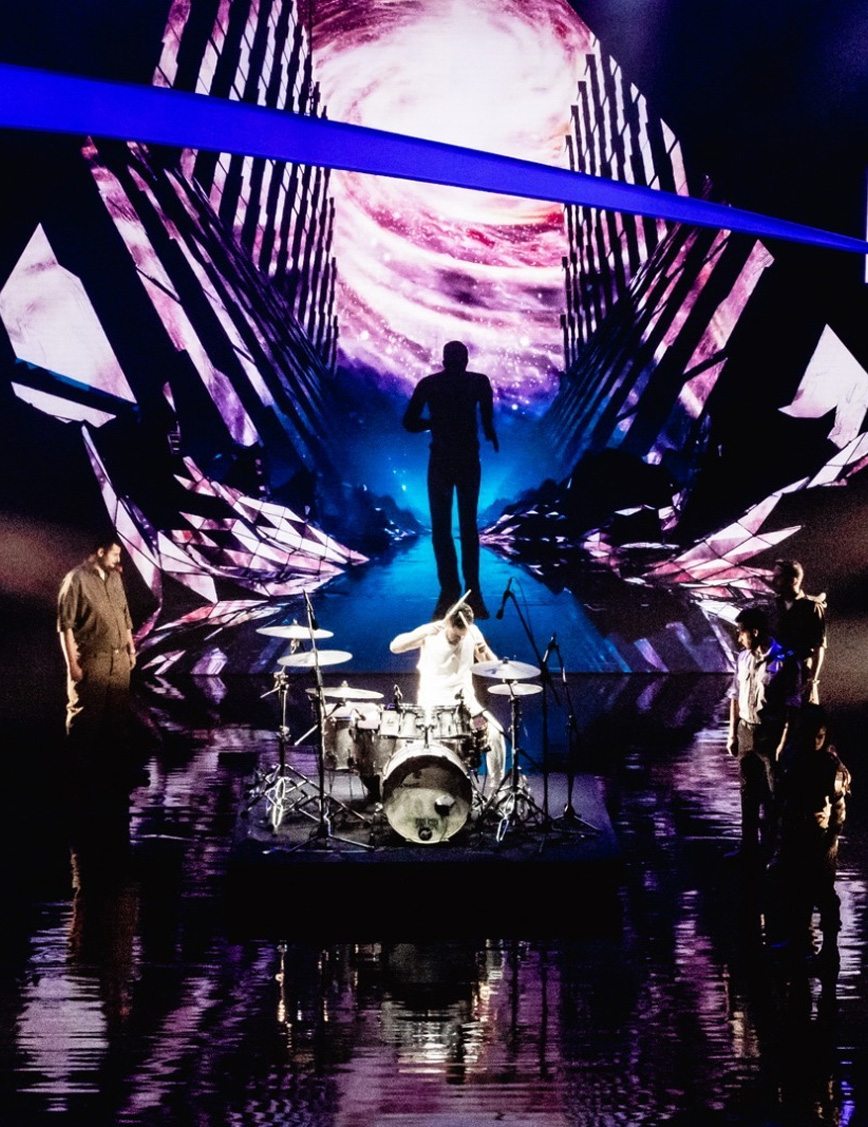 Drummer performing on a dramatic digital event stage.