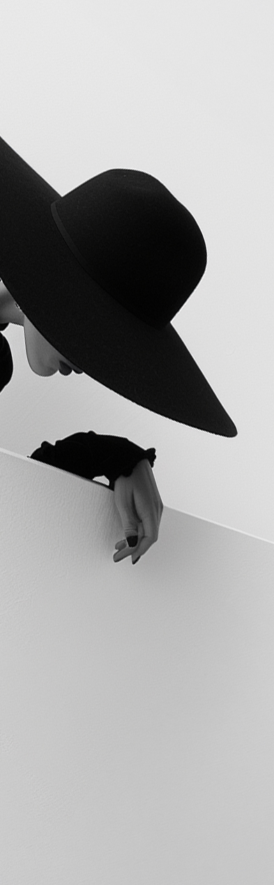 Black and white portrait detail with a wide-brim hat and hand.